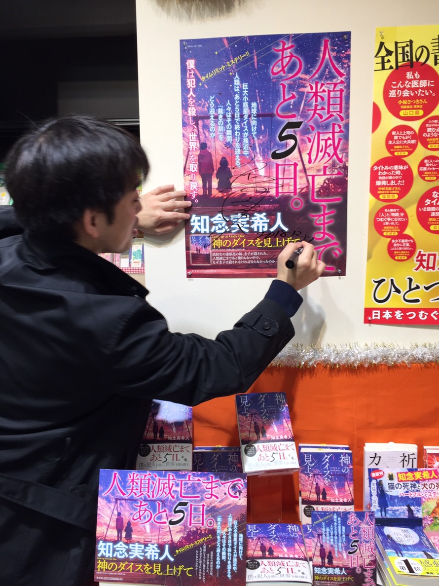 ポスターにサインする知念実希人さん。
